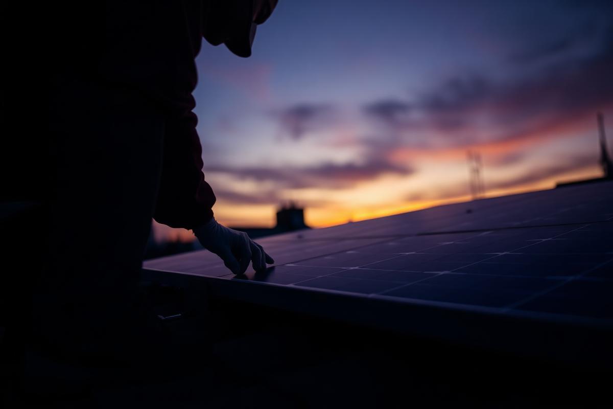 A technician installing a solar panel at dusk